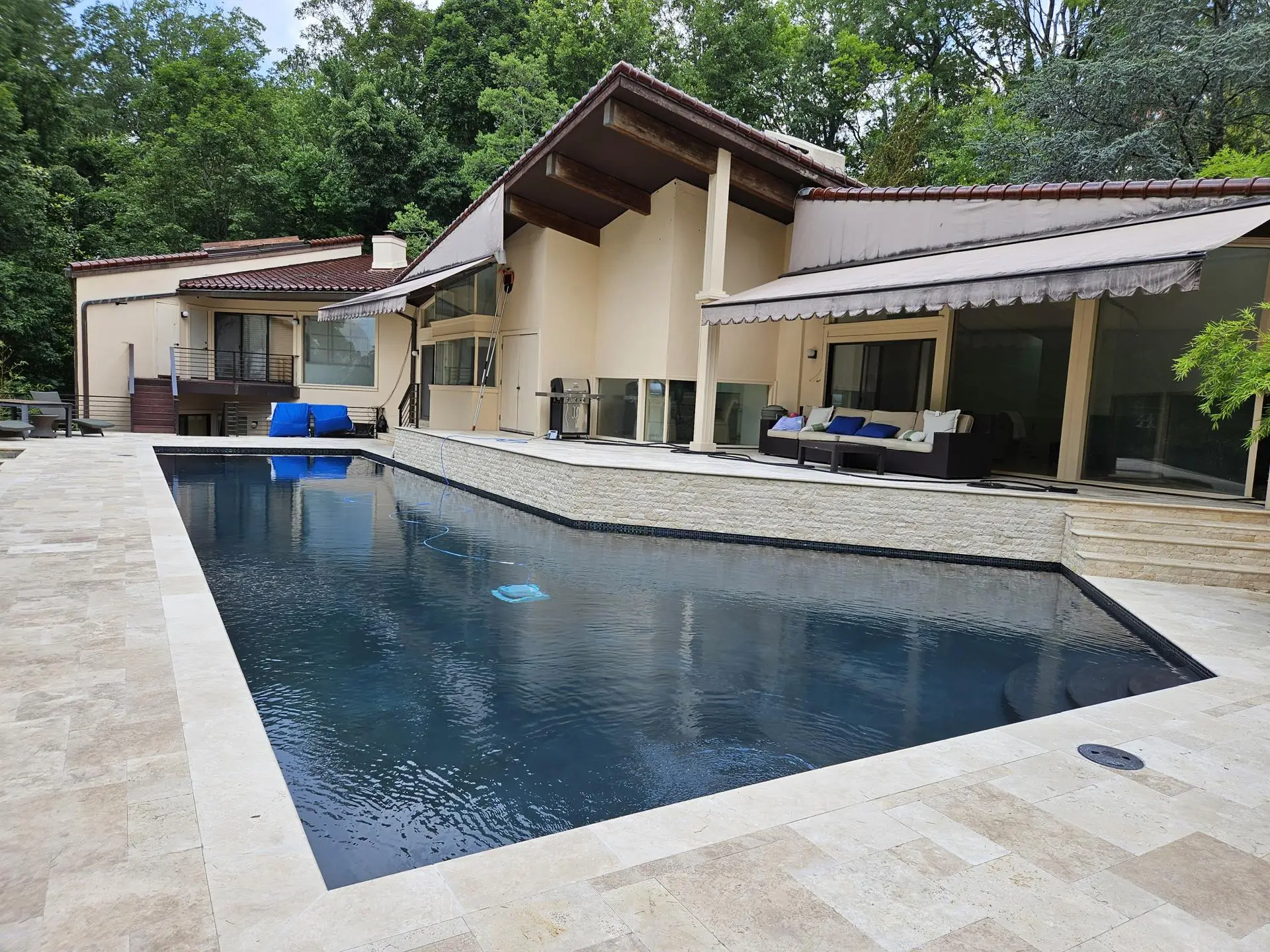 Modern gunite pool with dark plaster and travertine deck